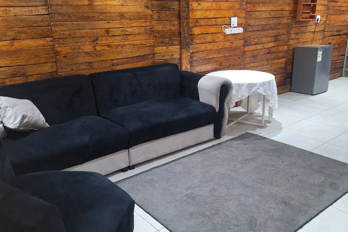 Living area featuring a rustic timber-clad feature wall, neutral tiled flooring, and modern recessed downlighting.