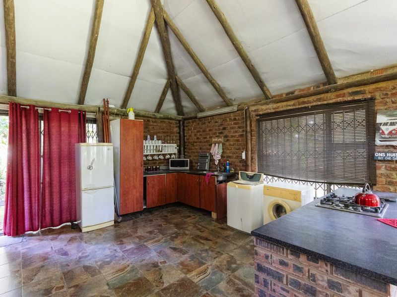 Rustic kitchen featuring exposed brick walls, timber rafters, slate flooring, and a brick island with a gas hob.
