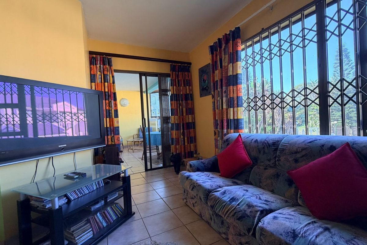 A living room featuring tiled flooring, security bars on the windows, and a sliding glass door leading to an adjacent patio area.