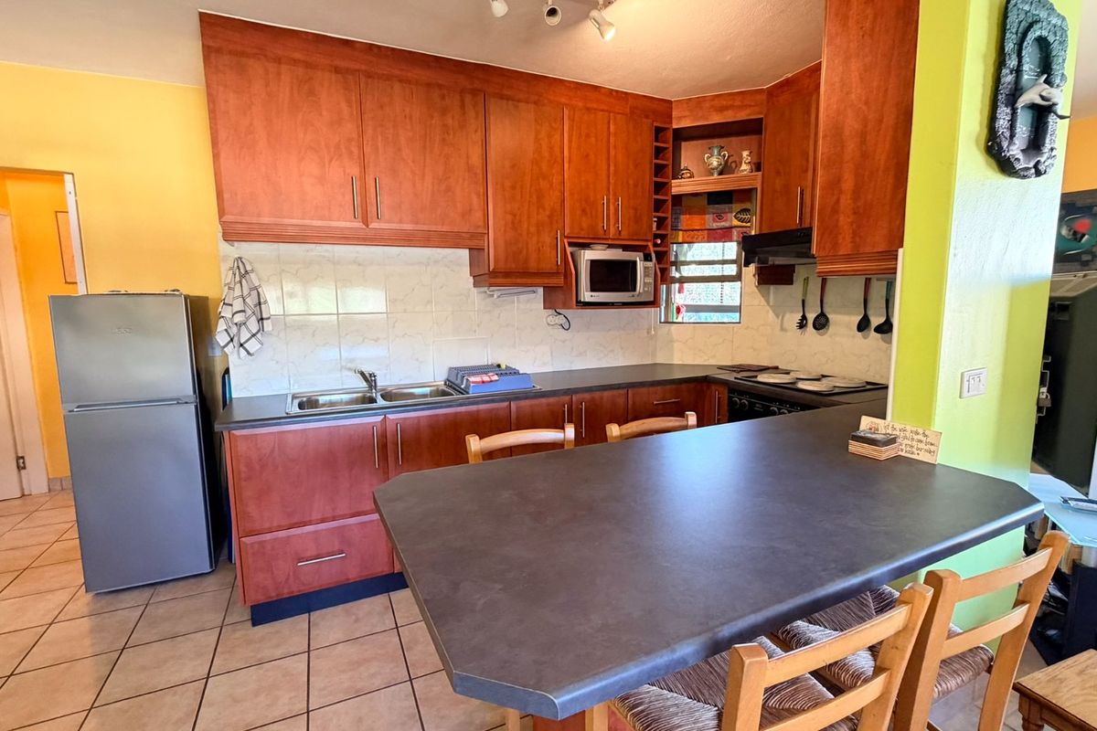 Functional kitchen featuring wooden cabinetry, laminate countertops, a breakfast bar, and tiled flooring, offering a practical layout for daily meal preparation.