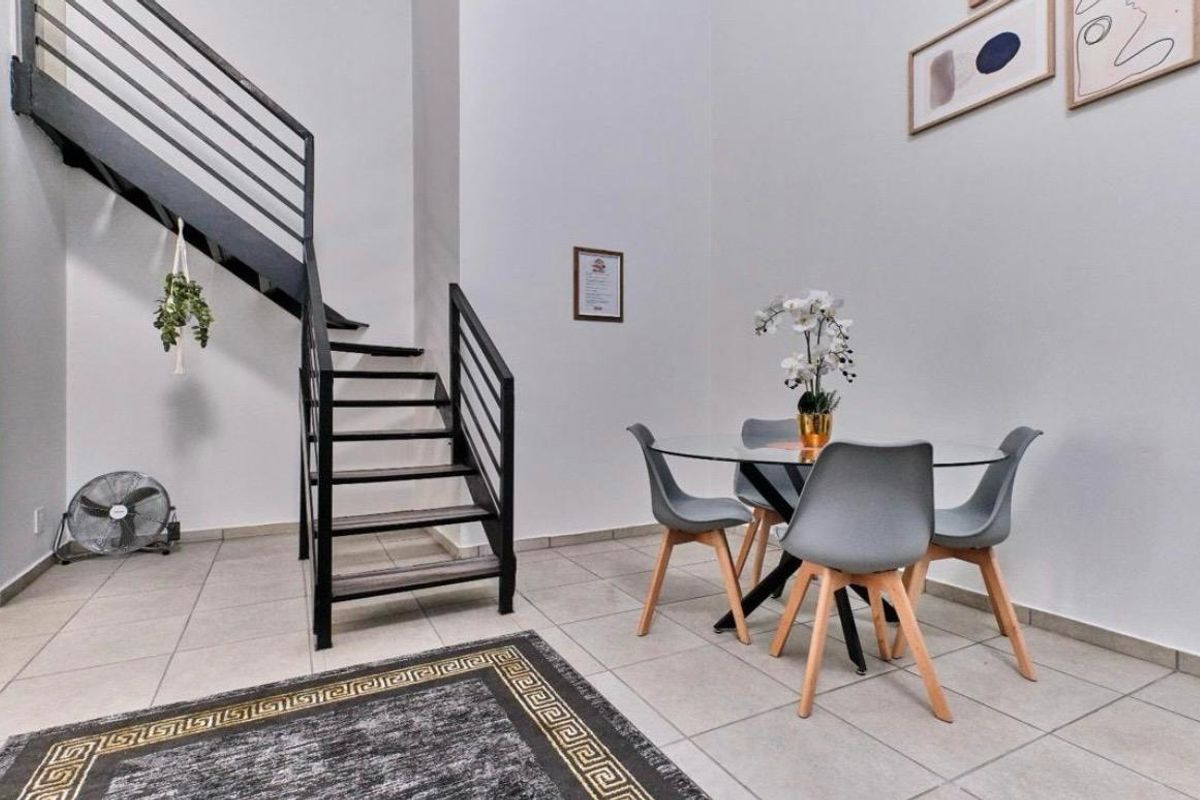 Open plan living area featuring a modern metal staircase and neutral tiled flooring, creating a bright and airy atmosphere.