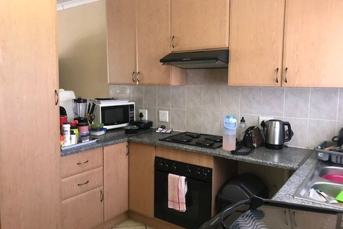 A functional kitchen featuring laminate cabinetry, built-in oven and hob, extractor fan, tiled backsplash, and a double bowl stainless steel sink.