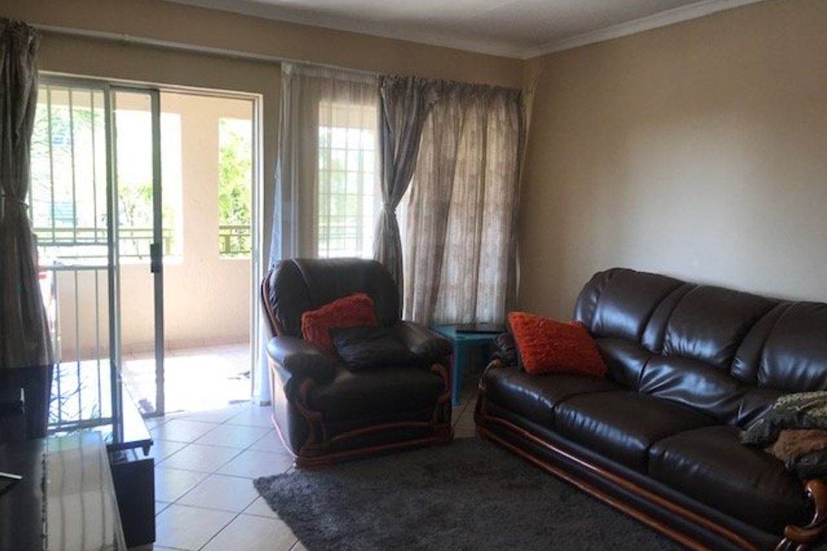 A living room featuring tiled flooring and a sliding glass door providing access to an outdoor balcony area.