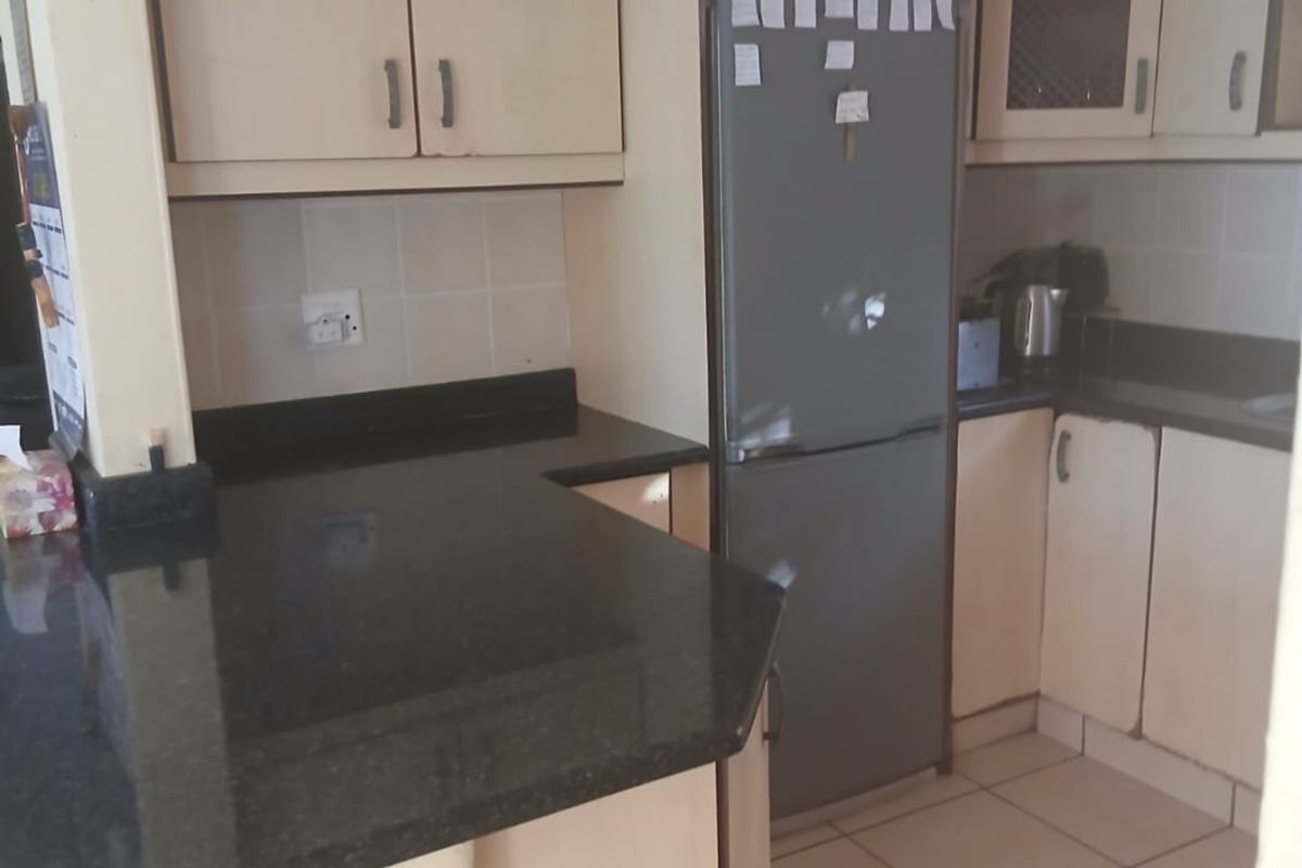 A functional kitchen featuring light-toned cabinetry, dark granite countertops, and tiled flooring, offering a practical layout for daily meal preparation.