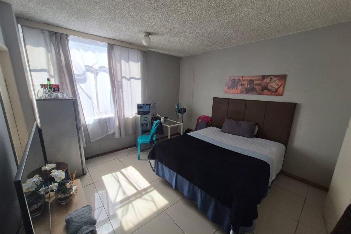 A functional bedroom featuring tiled flooring and a textured ceiling, offering a neutral base for personalization.