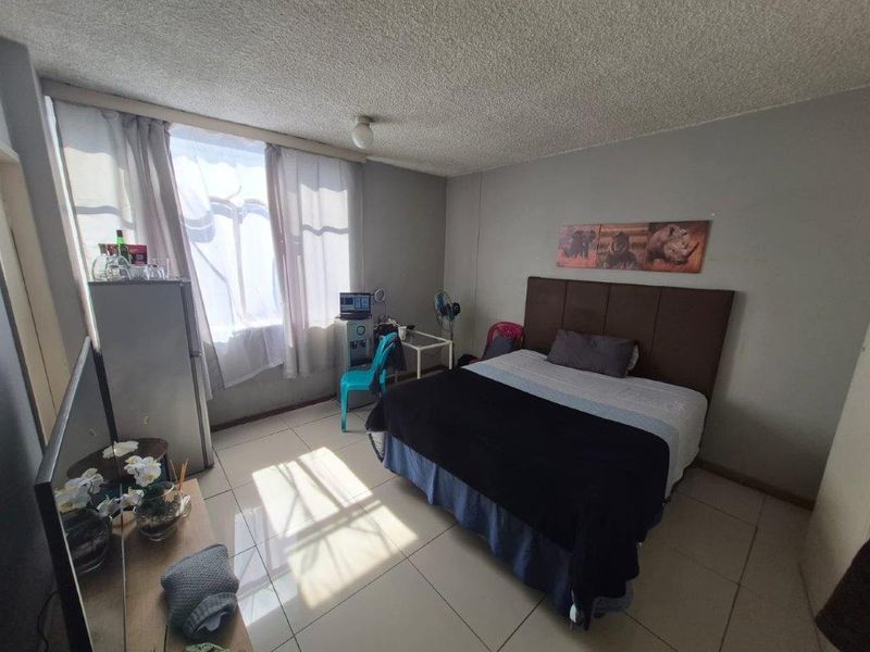 A functional bedroom featuring tiled flooring and a textured ceiling, offering a neutral base for personalization.