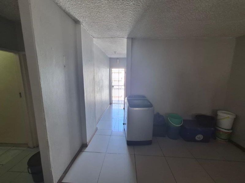 A functional laundry area featuring tiled flooring and a security gate, providing access to the exterior.