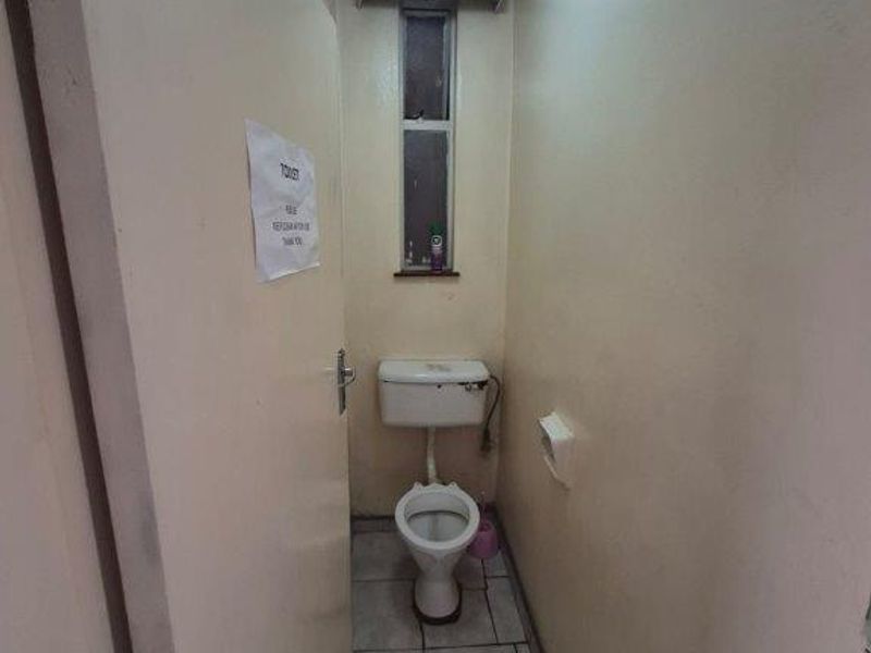 A compact, functional bathroom featuring a standard toilet, tiled flooring, and a small window, presenting an opportunity for cosmetic updates and modernization.