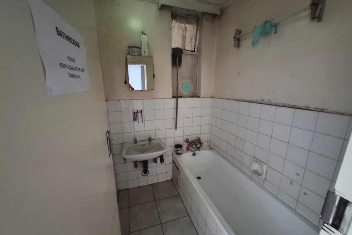 A dated bathroom featuring a standard bathtub and wall-mounted basin, requiring significant renovation and cosmetic updates to improve its condition and functionality.