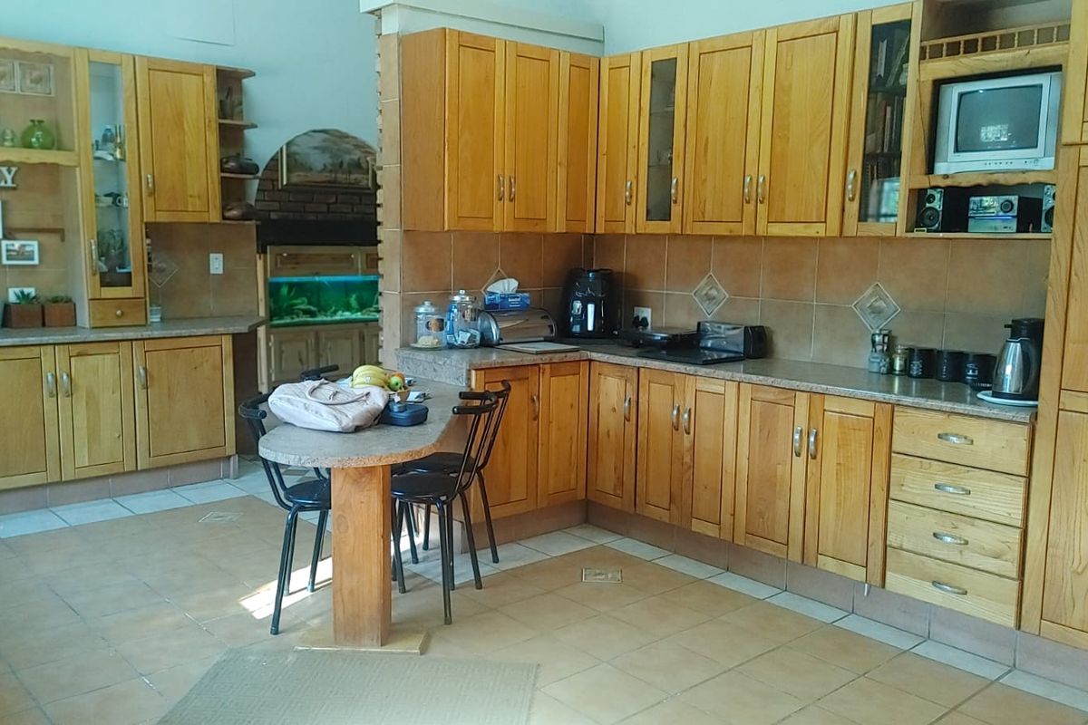 Spacious kitchen featuring extensive wooden cabinetry, stone countertops, tiled backsplash, and integrated appliances, offering a functional layout with ample storage space.