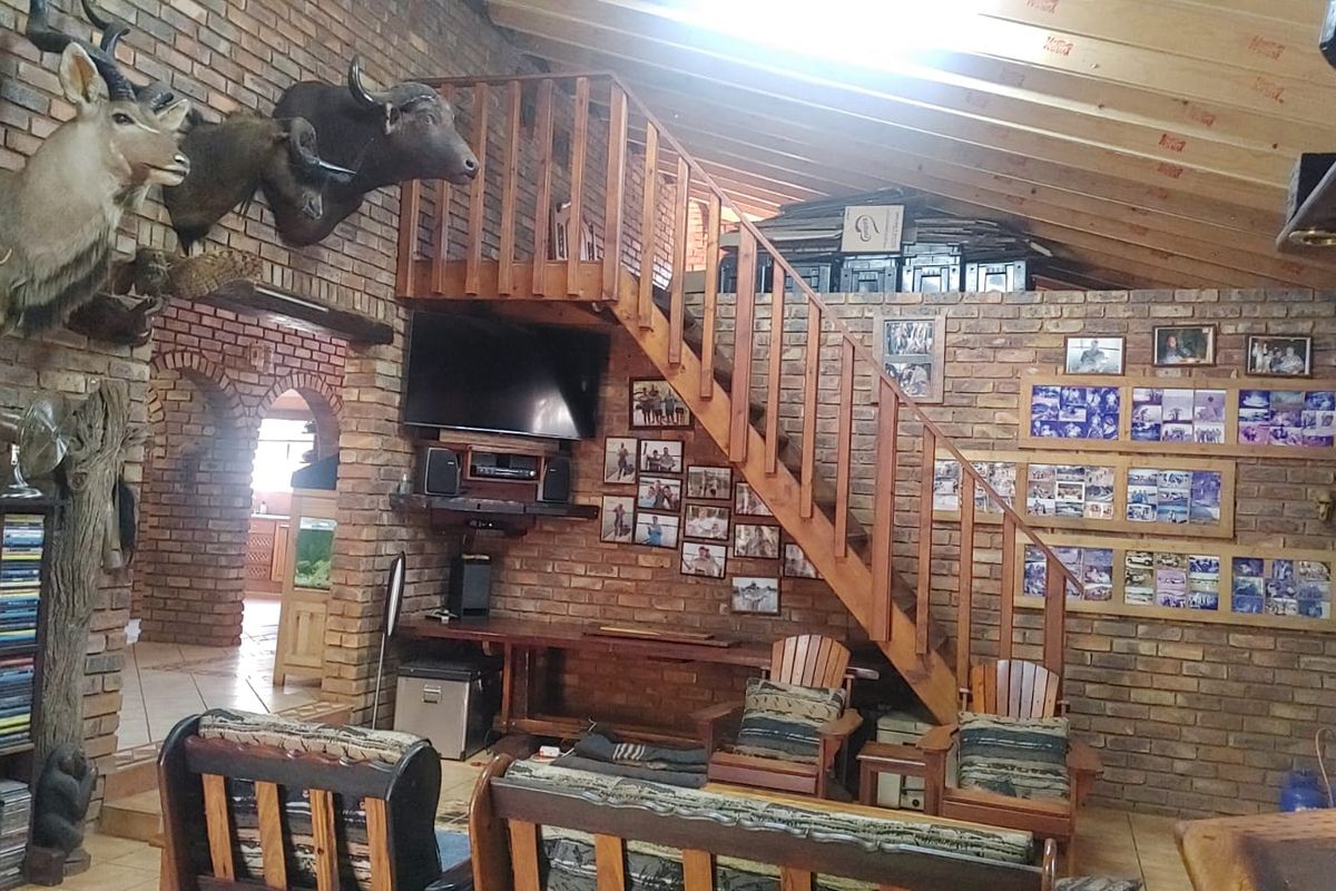 Spacious living area featuring exposed brick walls, a vaulted timber ceiling, and a wooden staircase leading to an upper level.