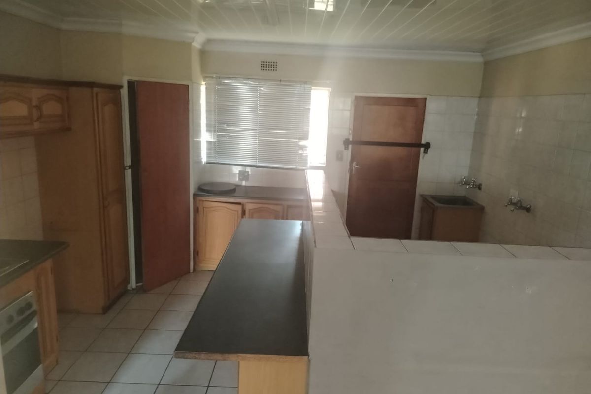 A functional kitchen featuring built-in wooden cabinetry, tiled splashbacks, and a breakfast bar, offering a dated layout ready for modern updates.