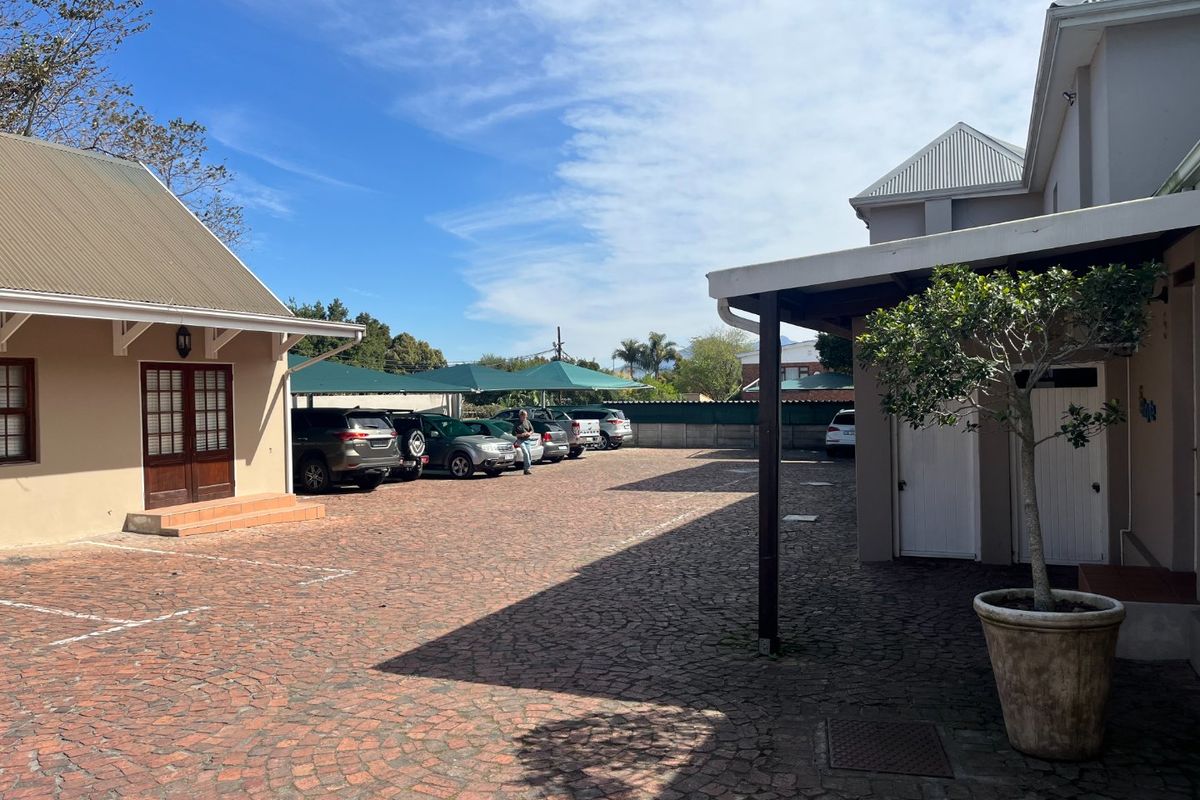 Commercial courtyard area featuring cobblestone paving, covered parking bays with shade sails, and access to adjacent building structures.