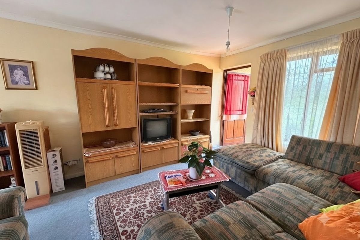 A living room featuring a large built-in wooden shelving unit, carpeted flooring, and a sliding glass door providing access to the exterior.