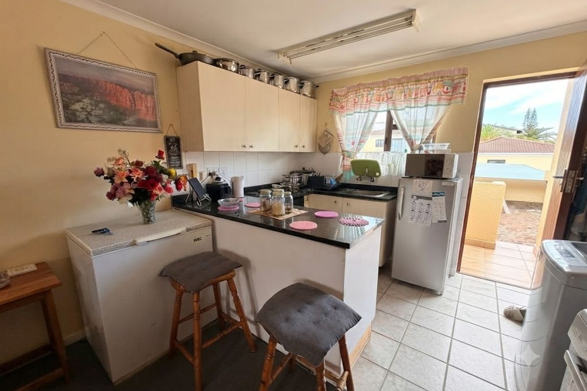 Compact kitchen featuring built-in cabinetry, laminate countertops, and direct access to an outdoor balcony area.