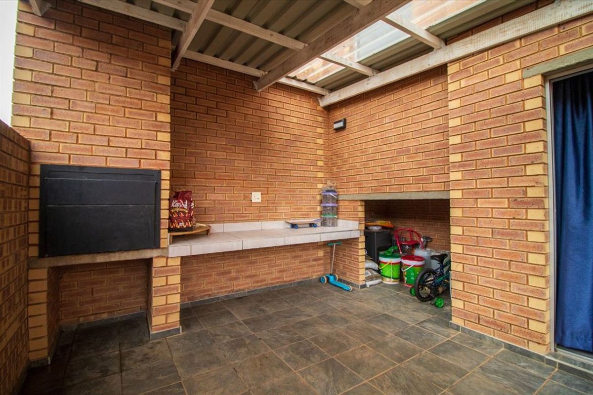 Covered patio area featuring a built-in braai, tiled workspace, and durable brick construction, ideal for outdoor entertaining.