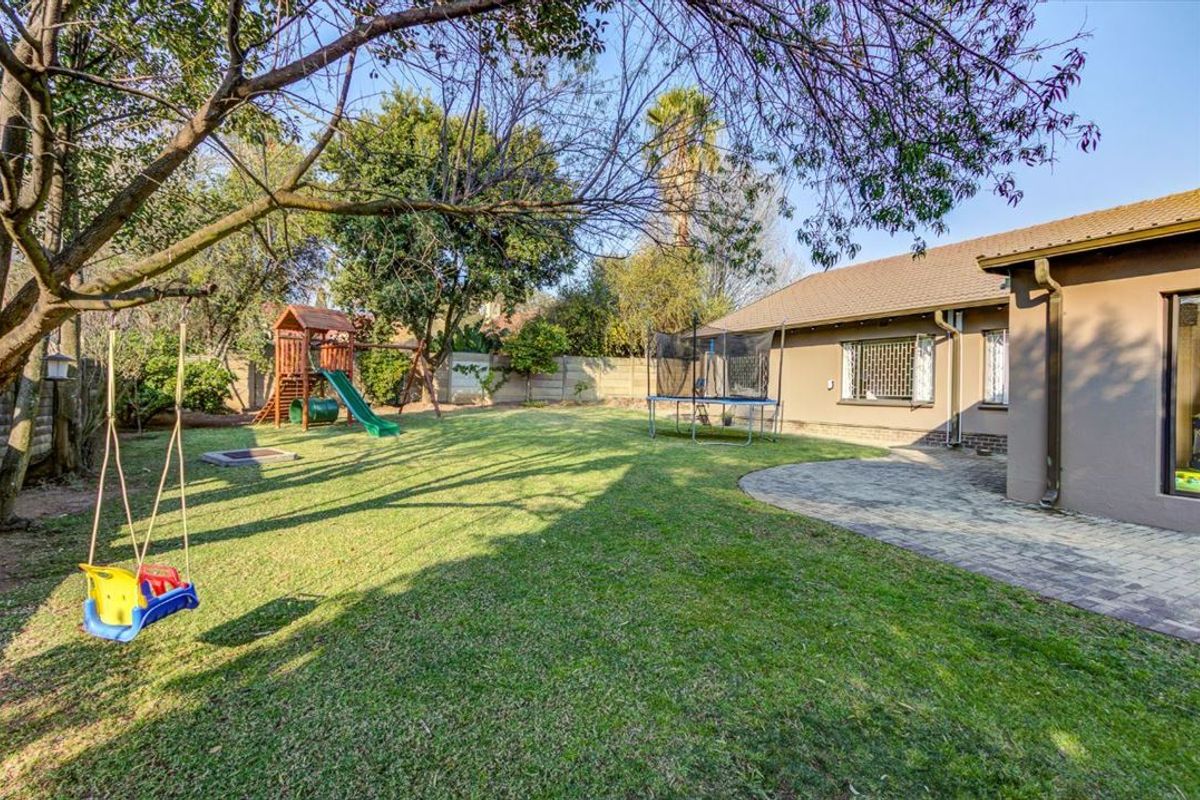 Spacious rear garden featuring a paved patio area, established lawn, and perimeter walling, providing a private outdoor space for the property.