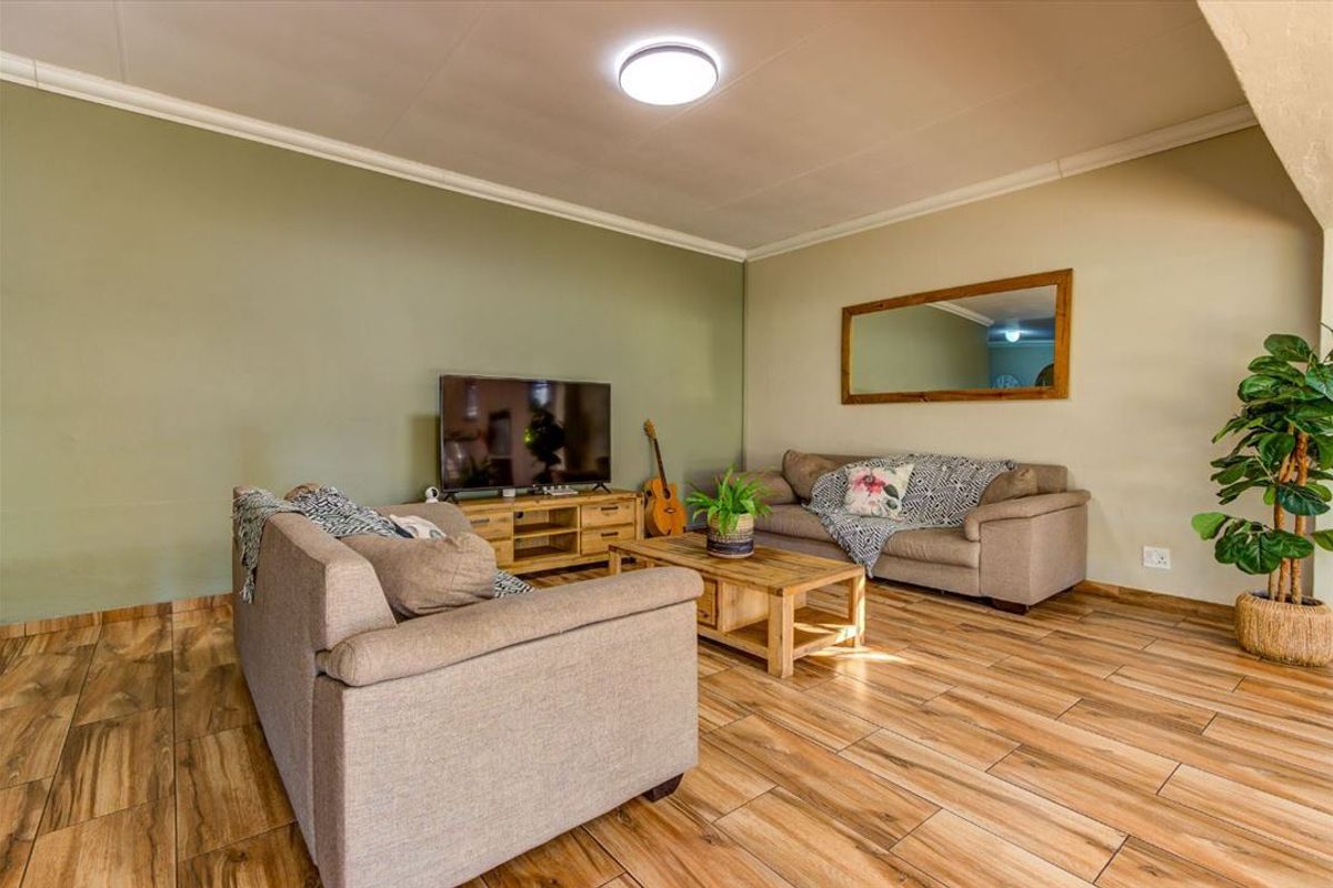 A comfortable living room featuring wood-look tile flooring, neutral wall tones, and a coved ceiling, providing a warm and inviting atmosphere.
