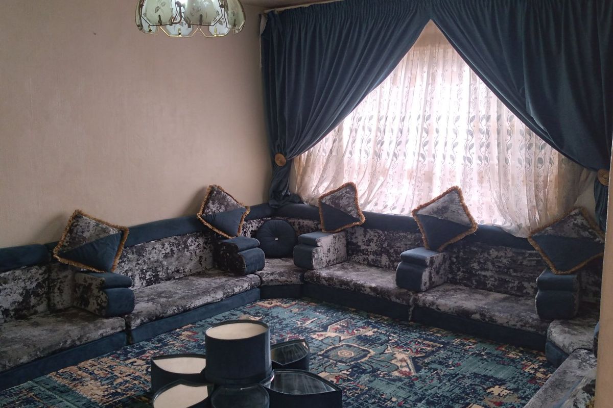 A living room space featuring a large window with heavy drapes and a central ceiling light fixture.