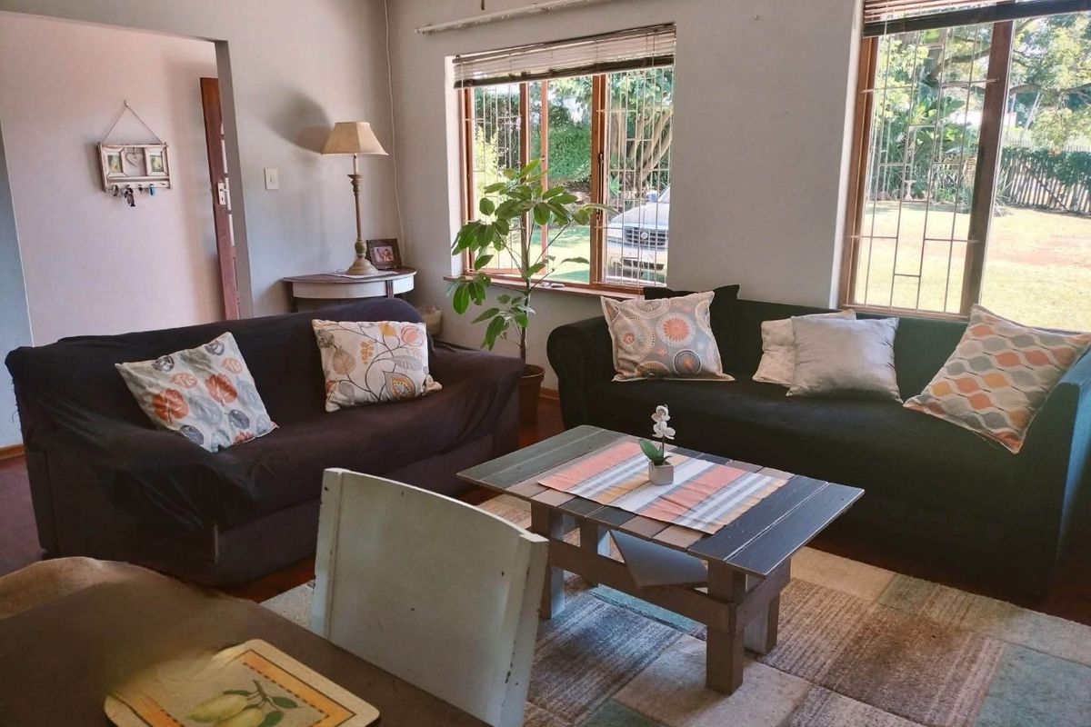 A comfortable living room featuring timber-framed windows with security bars, providing natural light and views of the garden.