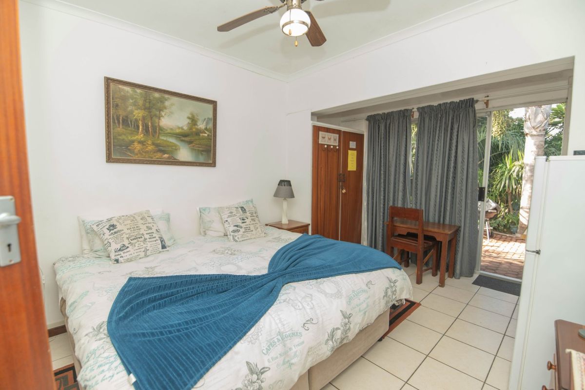 A bedroom featuring tiled flooring, a ceiling fan, and a sliding glass door providing direct access to an outdoor patio area.