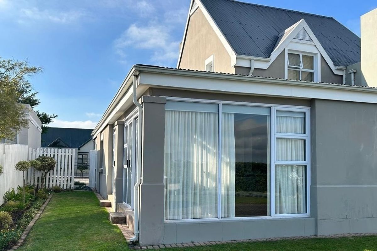 Rear view of the property featuring a modern extension with large aluminium sliding doors, corrugated metal roofing, and a well-maintained garden area.