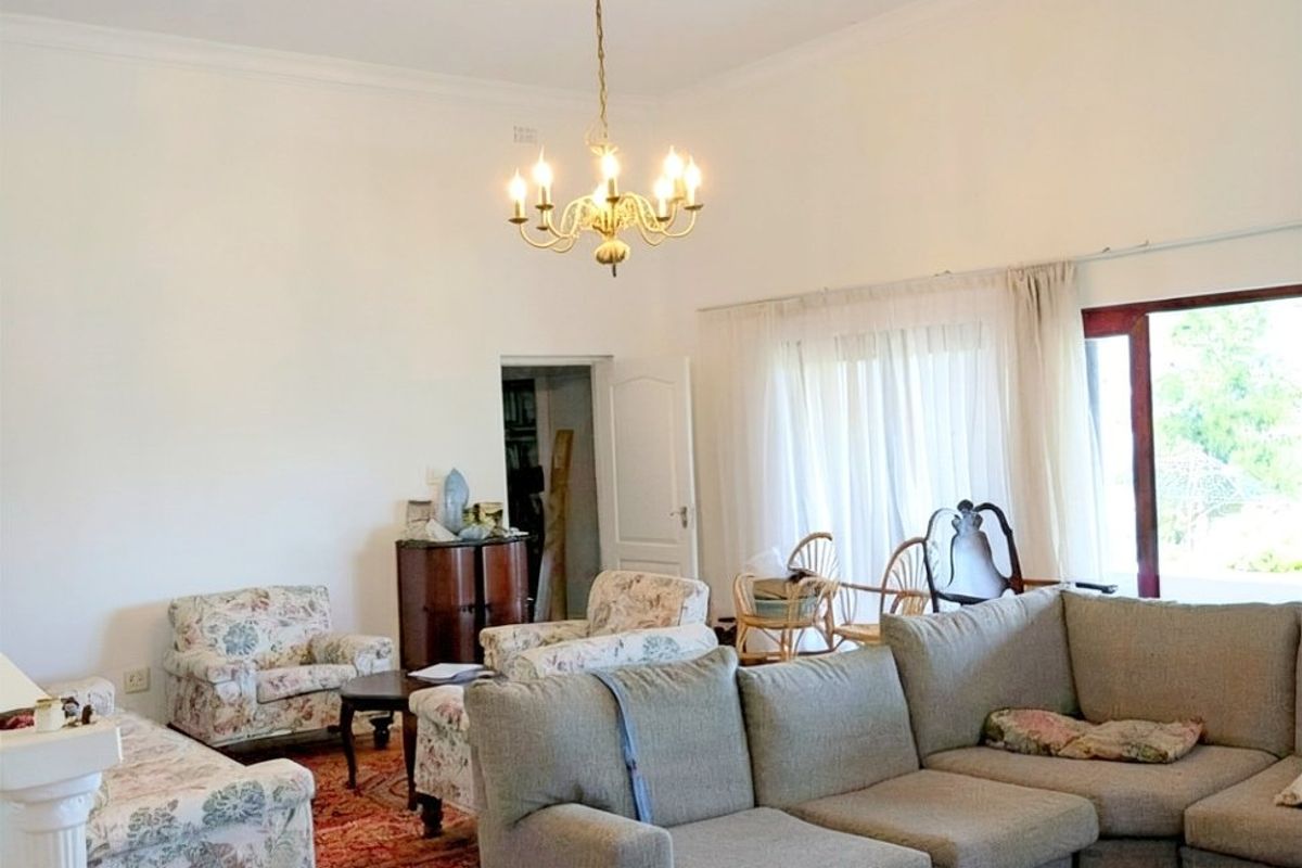 Spacious living room featuring high ceilings, a classic chandelier, and large sliding glass doors providing natural light and access to the outdoors.