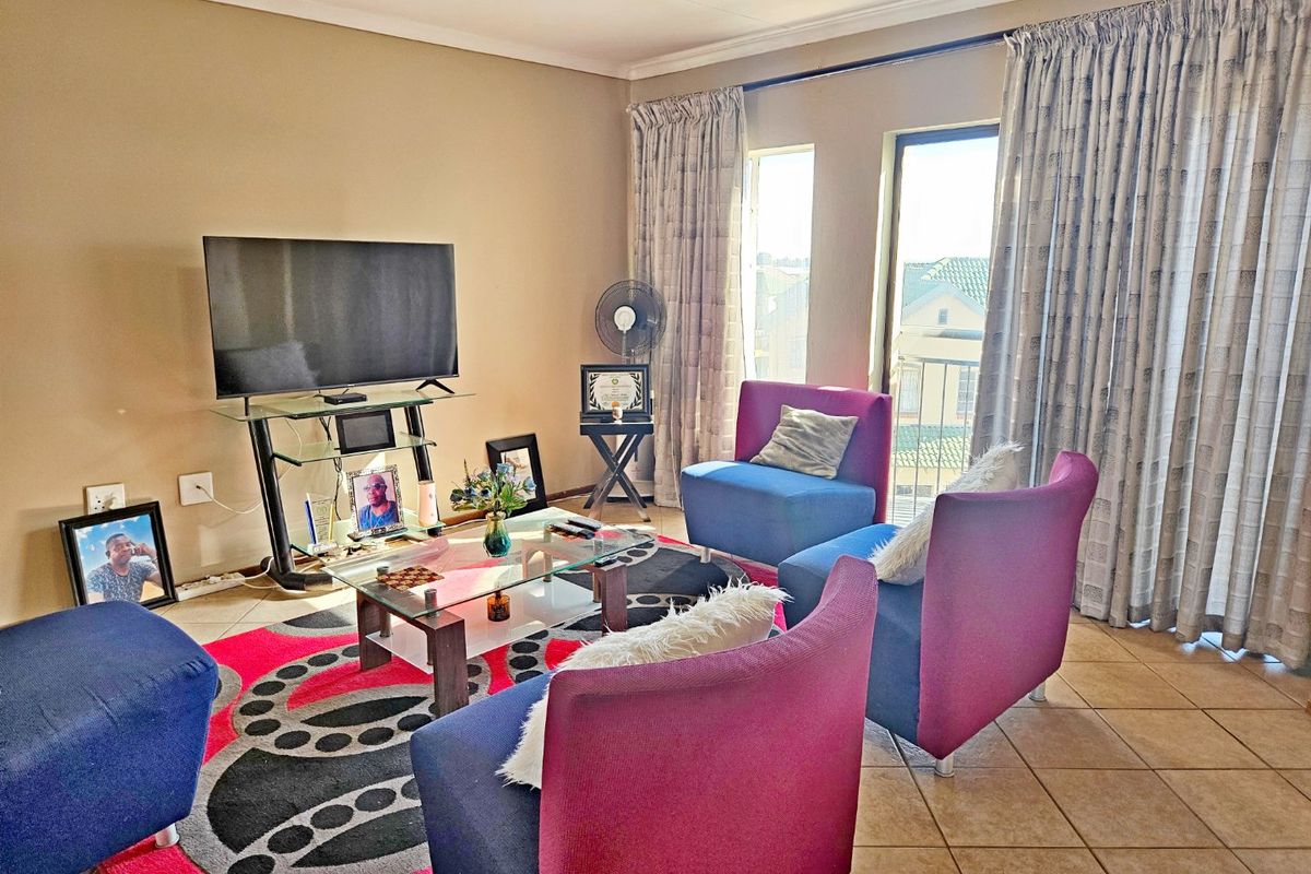 A living room area featuring tiled flooring and a sliding glass door providing access to an outdoor space.