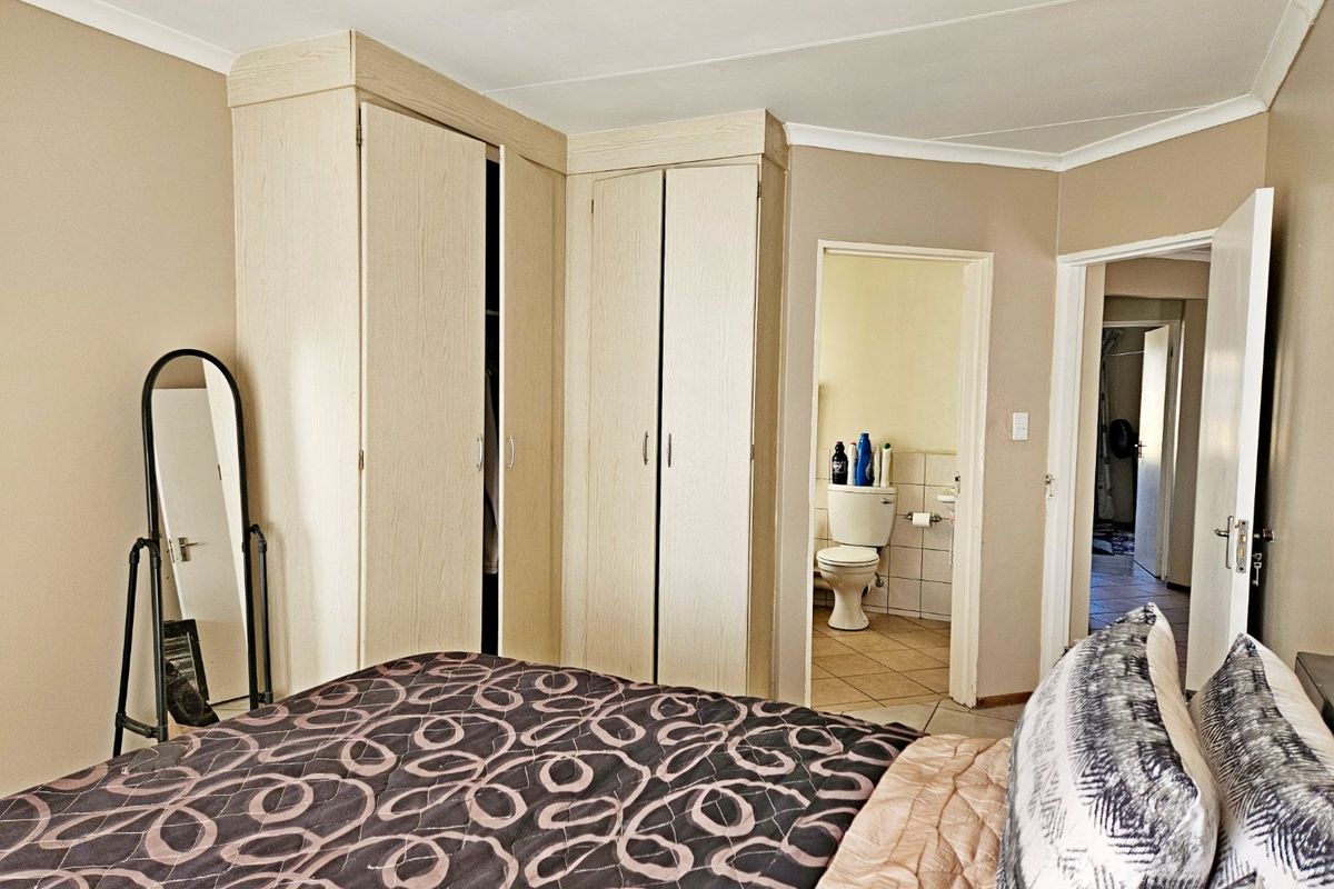 Bedroom featuring light wood-finish built-in cupboards and direct access to an en-suite bathroom.