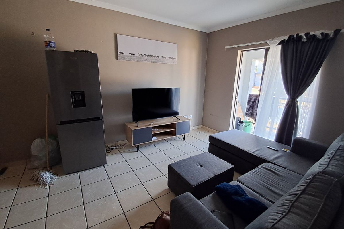 A living room area featuring tiled flooring and a sliding glass door providing access to an outdoor space.