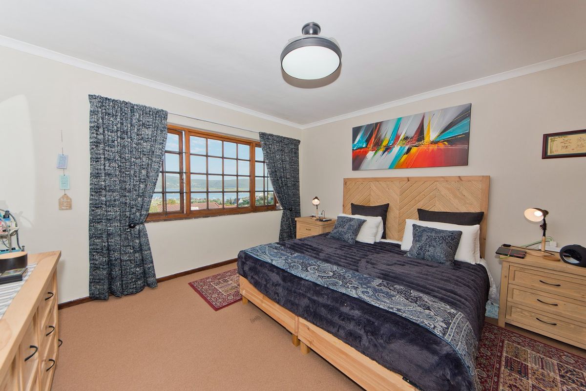 A well-maintained bedroom featuring a timber-framed window with views, neutral wall finishes, and a ceiling light fixture.