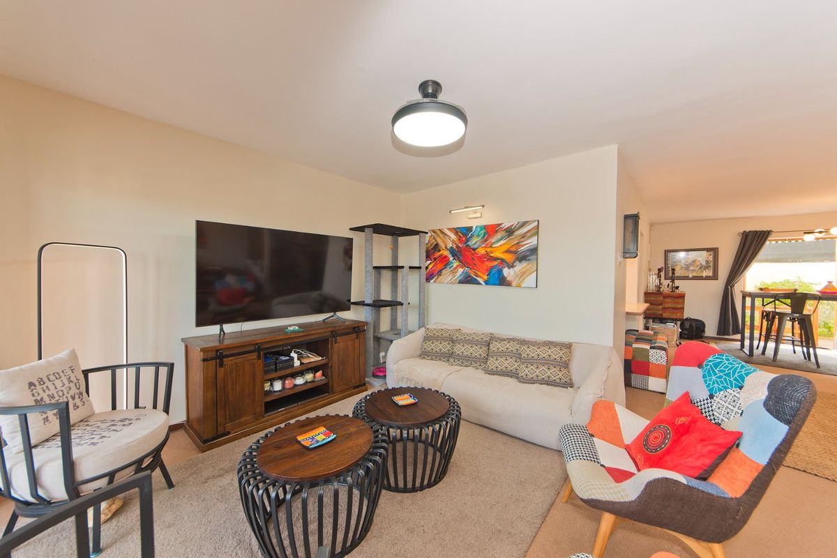 A comfortable living room area featuring neutral wall tones, a central ceiling light, and an additional wall-mounted light fixture.