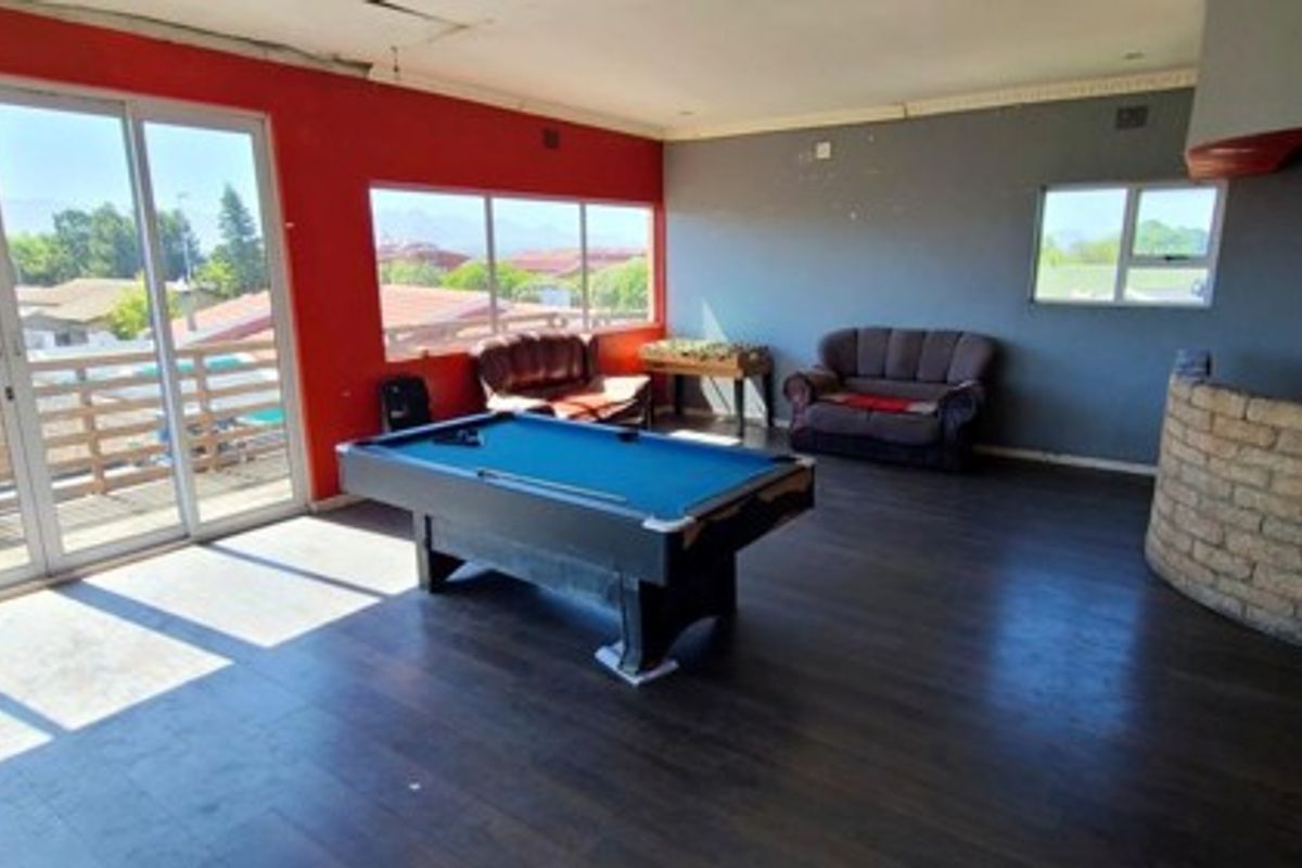 Spacious living area featuring large sliding doors, laminate flooring, and a unique brick fireplace, offering potential for a modern entertainment space.