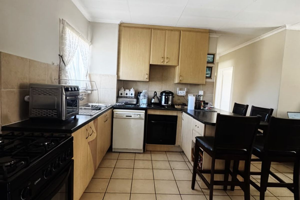 A functional kitchen featuring built-in cabinetry, tiled flooring, a tiled backsplash, and integrated appliances, offering a practical layout for daily use.