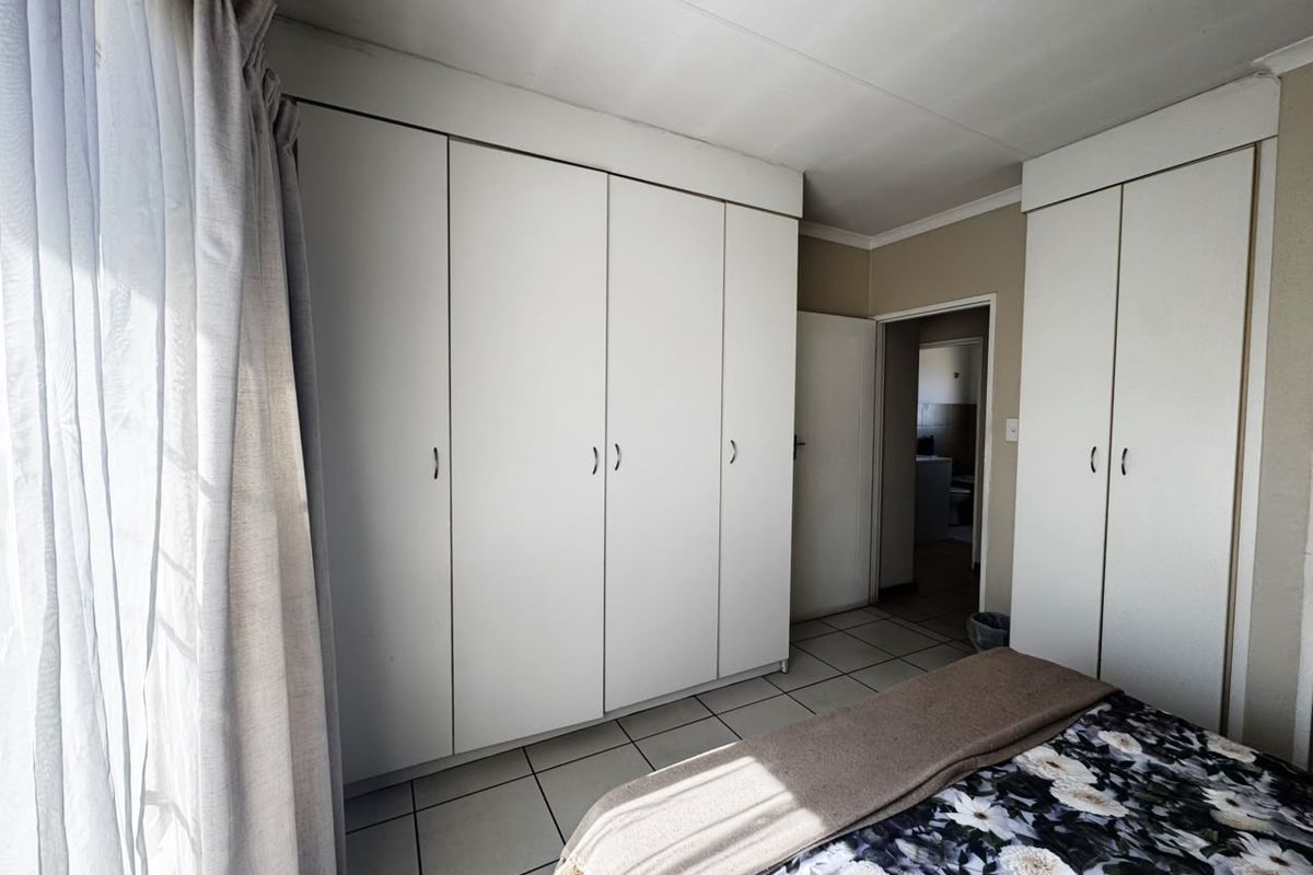 A bedroom featuring extensive white built-in cupboards and tiled flooring, offering ample storage space and a neutral foundation for interior design.