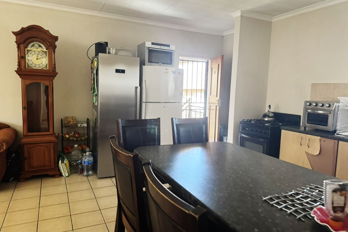 Open plan kitchen and dining area featuring tiled flooring, built-in cabinetry, and a gas stove, with direct access to an exterior security door.