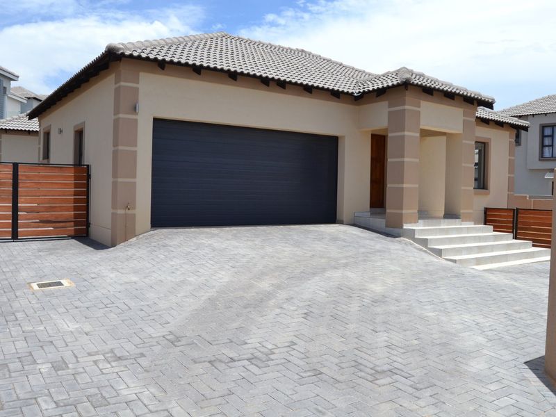 Front elevation of a modern house featuring a paved driveway, double garage, and concrete entrance steps.