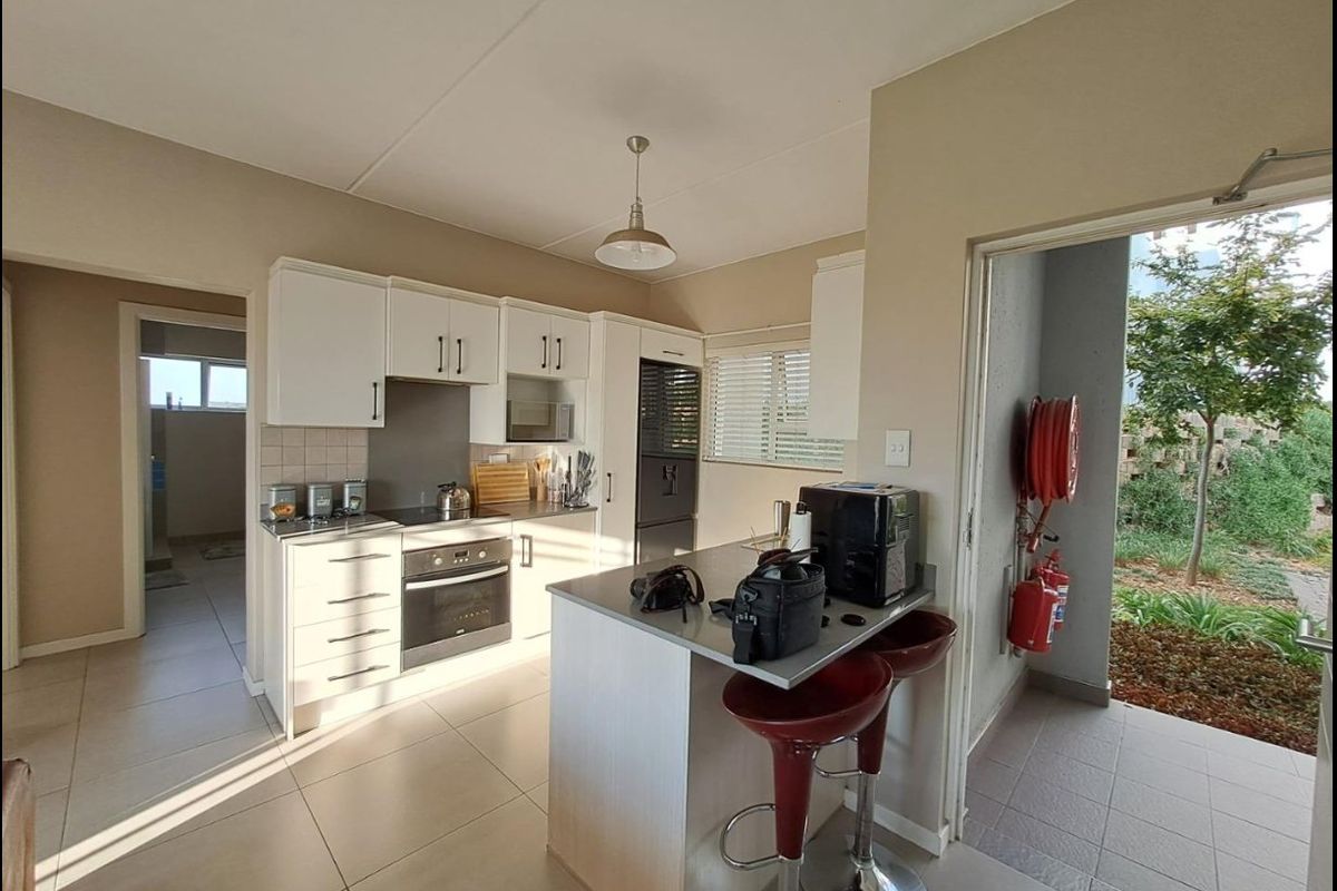Modern kitchen featuring white cabinetry, stone countertops, integrated appliances, and direct access to an outdoor area with fire safety equipment.