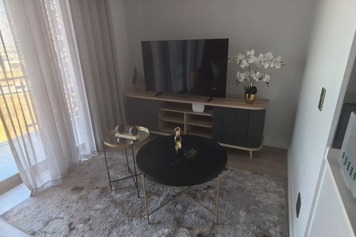 A bright living area featuring laminate flooring and a large sliding glass door providing access to the balcony.