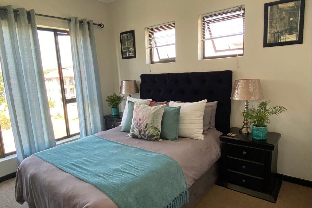 A well-lit bedroom featuring carpeted flooring, multiple casement windows, and neutral wall finishes, providing a comfortable and functional sleeping space.