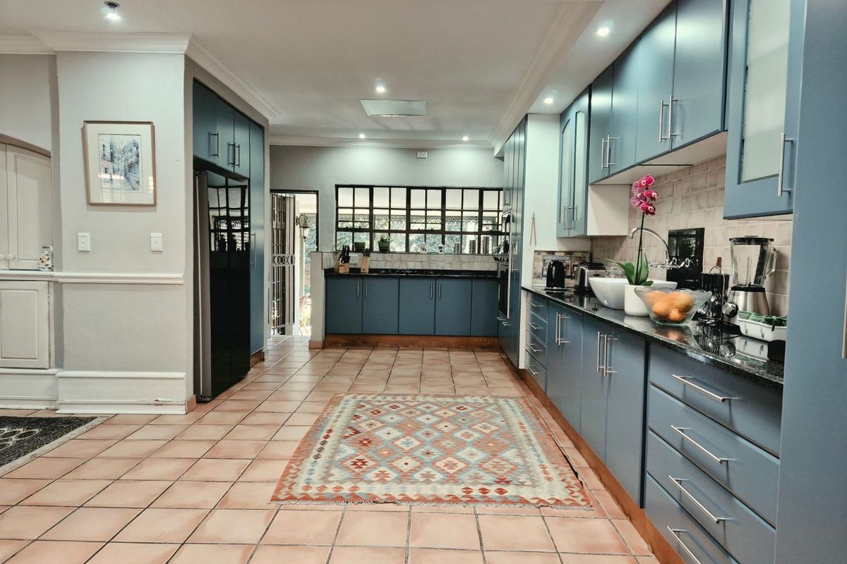 Spacious kitchen featuring blue cabinetry, granite countertops, tiled flooring, and recessed lighting, offering a functional and well-maintained workspace.
