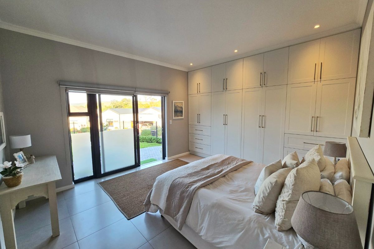 A well-maintained bedroom featuring extensive built-in cabinetry, tiled flooring, and sliding glass doors providing direct access to the outdoor area.