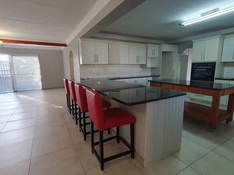 Spacious open-plan kitchen and living area featuring white cabinetry, granite countertops, integrated appliances, and large sliding doors leading to the exterior.