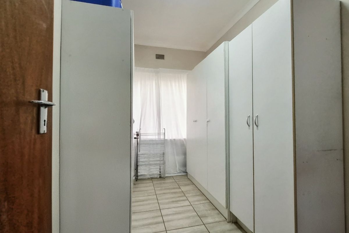 A bedroom featuring built-in cupboards and tiled flooring, providing functional storage space.