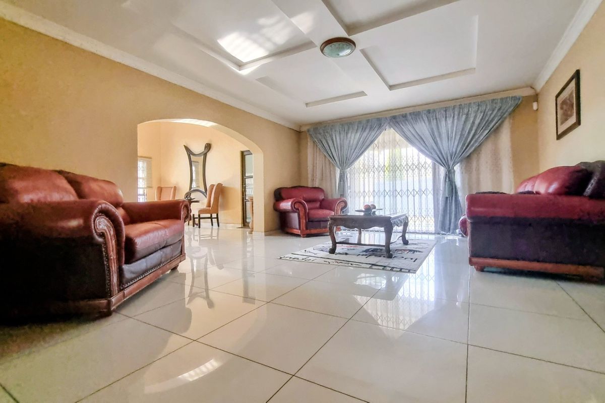 Spacious living room featuring a coffered ceiling, polished tile flooring, and an elegant archway leading to an adjacent area.