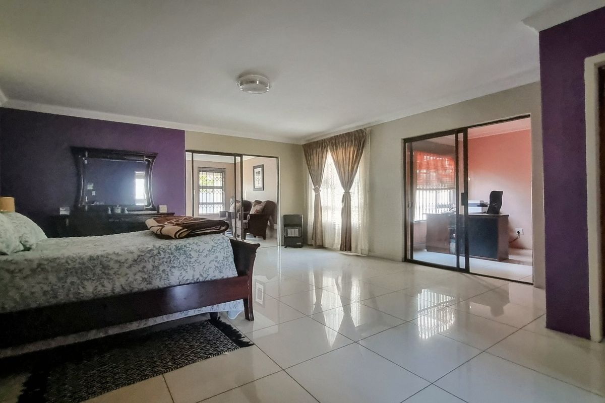 Spacious bedroom featuring polished tiled flooring, coved ceilings, and sliding glass doors providing access to an adjoining room.