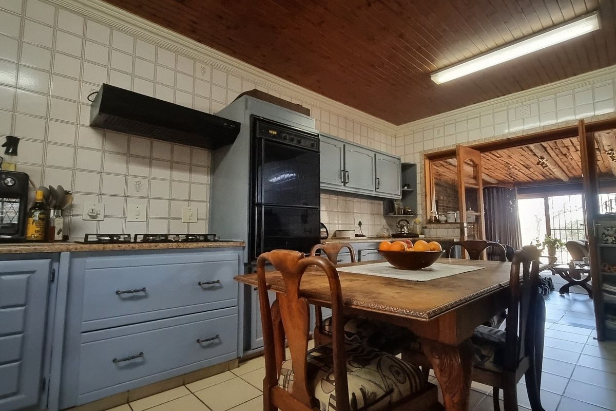 A functional kitchen featuring built-in cabinetry, a gas hob, and an integrated oven, with a timber ceiling and tiled splashback throughout.
