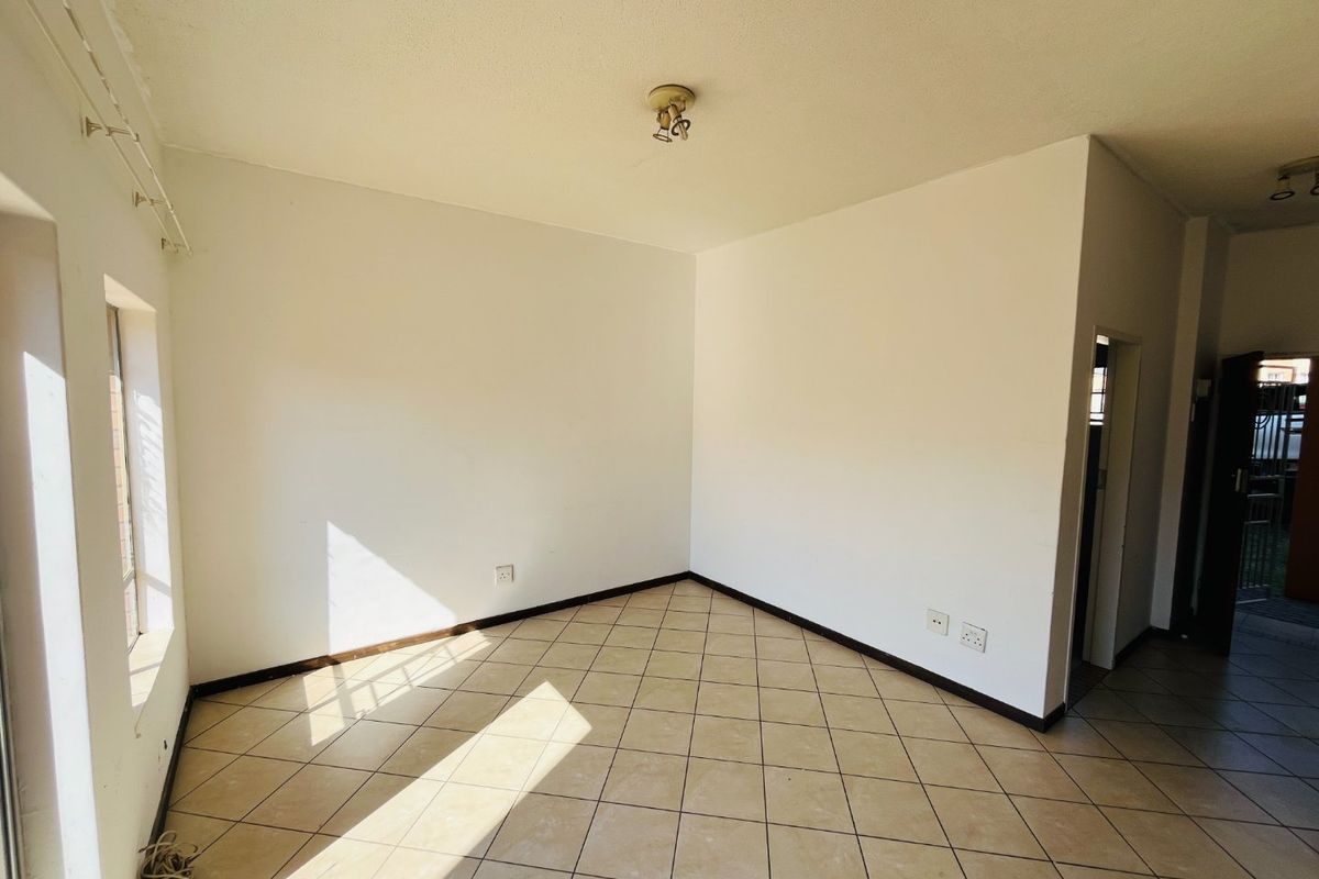 A bright, empty living room featuring neutral tiled flooring and clean white walls, offering a versatile space ready for personalization.