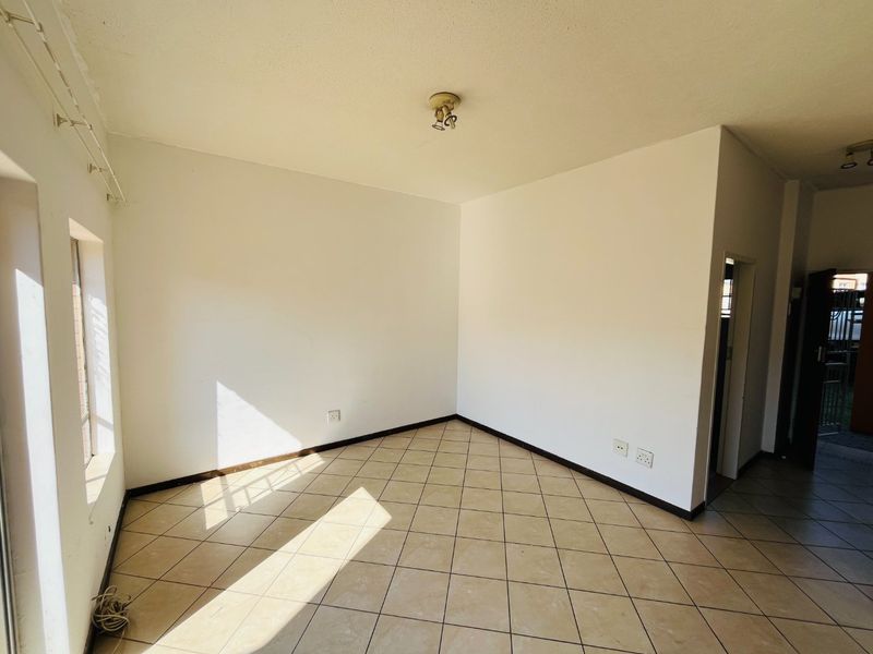A bright, empty living room featuring neutral tiled flooring and clean white walls, offering a versatile space ready for personalization.
