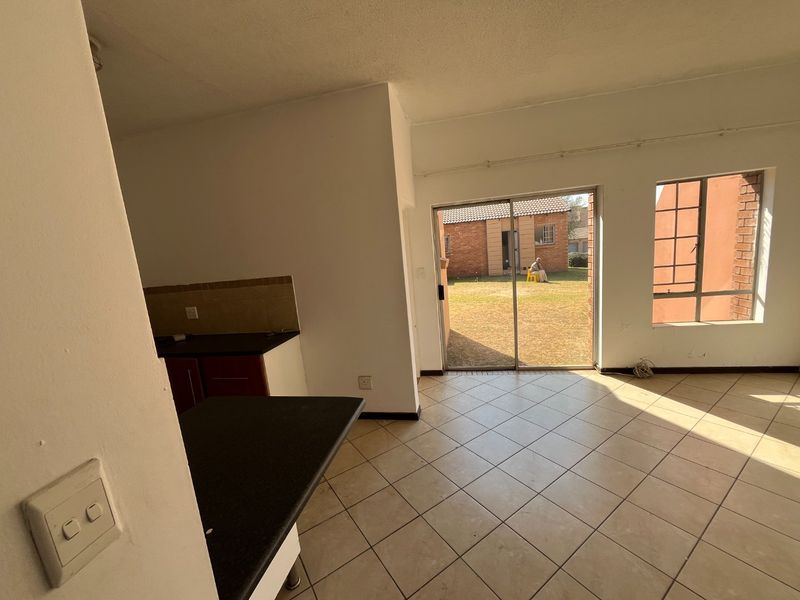 Open-plan living area featuring tiled flooring, kitchen cabinetry with dark countertops, and a sliding glass door providing access to the rear garden.